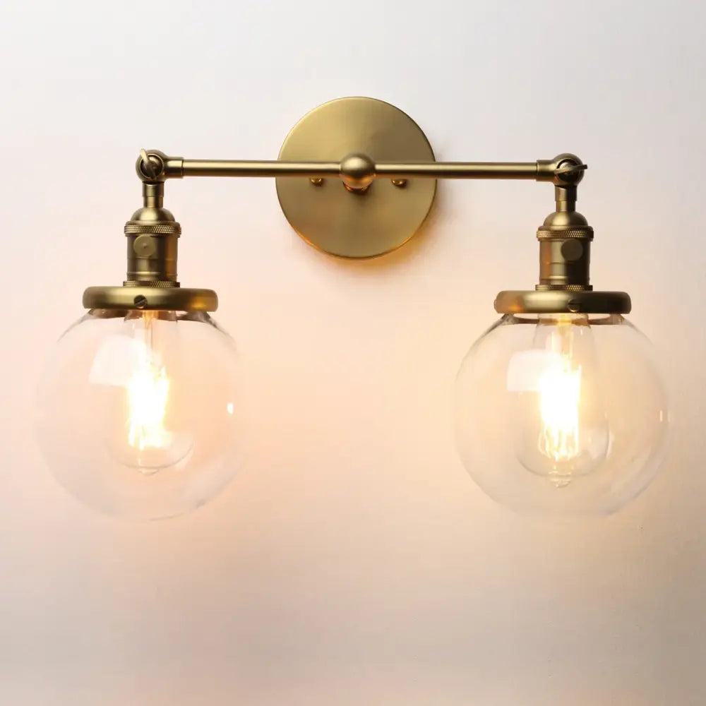 Brass-finished wall sconce with double ball heads glass globes and vintage edison bulbs for bedroom lighting