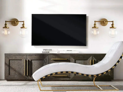 White upholstered chaise lounge with gold-tone metal frame and black and gold striped trim near modern vintage double ball heads globe wall sconce