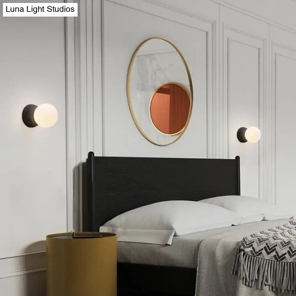 Gold-framed oval mirror with warm reflective surface complementing modern volcanic stone white glass wall lamp inch fixture