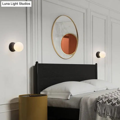 Gold-framed oval mirror with warm reflective surface complementing modern volcanic stone white glass wall lamp inch fixture