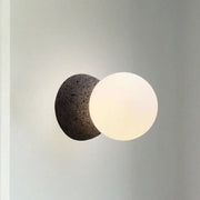Modern wall lamp with dark volcanic stone bulb base and smooth white glass shade for stylish living room decor