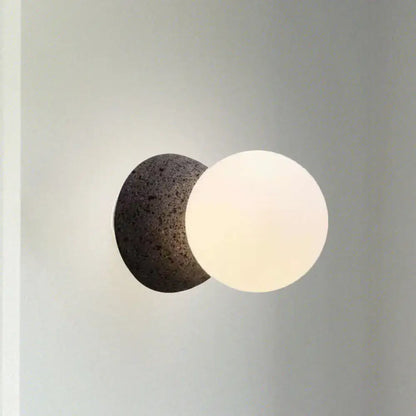 Modern wall lamp with dark volcanic stone bulb base and smooth white glass shade for stylish living room decor