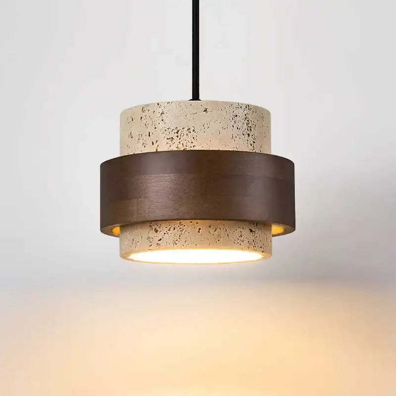 Modern wabi sabi tiered stone pendant light with textured beige concrete and bronze ring emitting warm led bulb glow