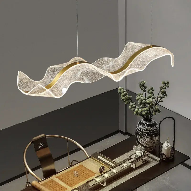 A modern wave gold acrylic led pendant lamp with a translucent textured body and gold-accented edges for dining room