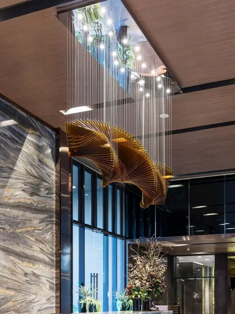 Modern wave golden designer chandelier with intricate metallic filigree suspended by thin cables for dining room decorbites designer chandelier