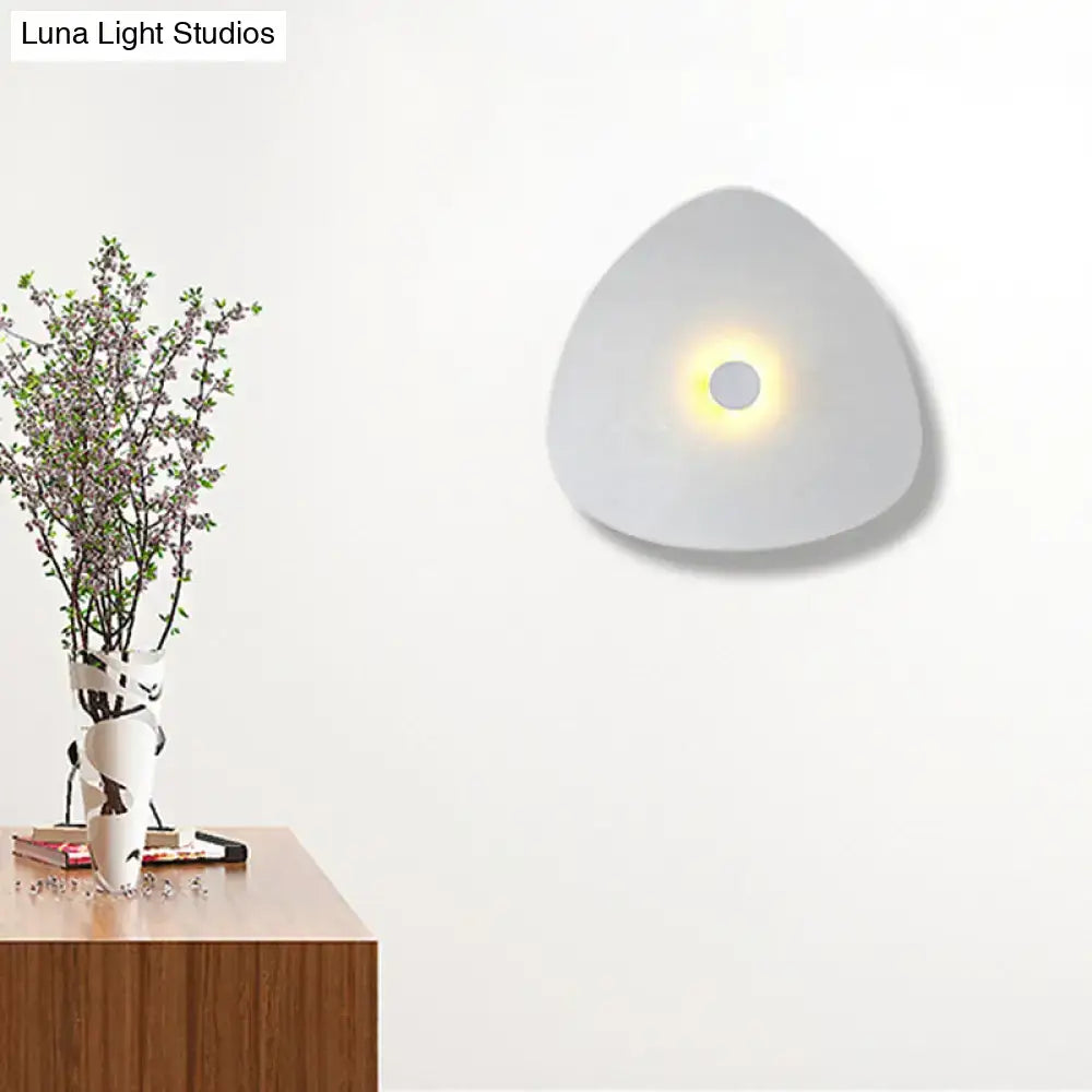 Modern white acrylic flaky sconce light with a triangular shape and soft glowing circular light for bedroom walls