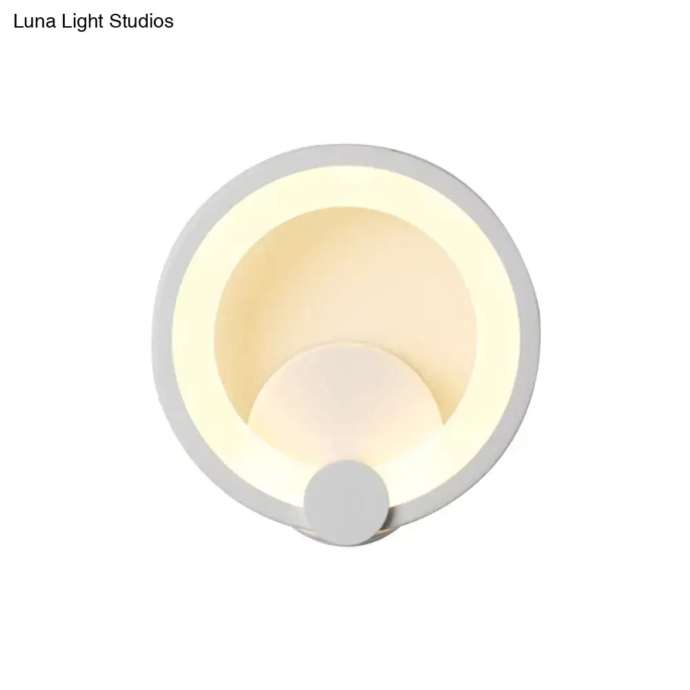 Modern white acrylic sconce light with circular concentric ring design emitting warm ambient light for bedroom use