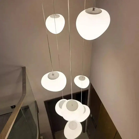 Modern white acrylic sphere pendant chandelier with frosted glass shades and metallic fixtures as a focal point for staircase design