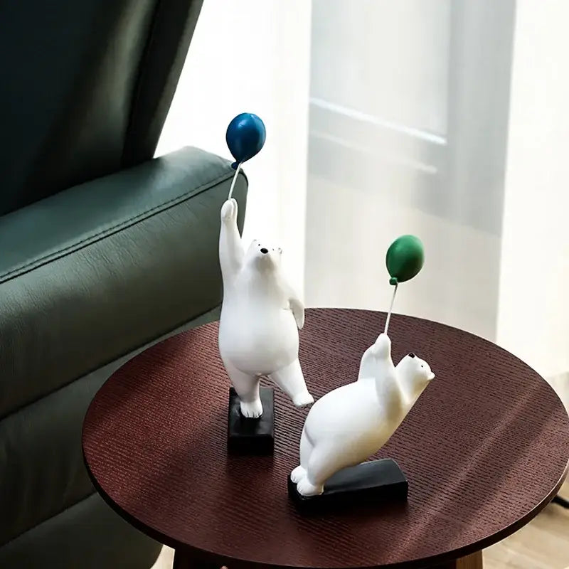 Two white polar bear figurines holding blue and green flying bear balloons on black bases for decorbites flying bear decor