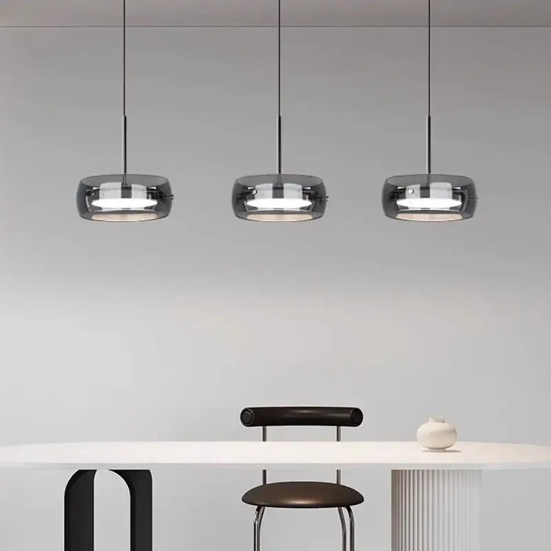 Three sleek modern pendant lights with dark smoked glass shades and remote dimming for minimalist dining rooms