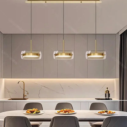 Three modern white pendant lights with clear glass shades and gold metal frames for remote dimming dining room use