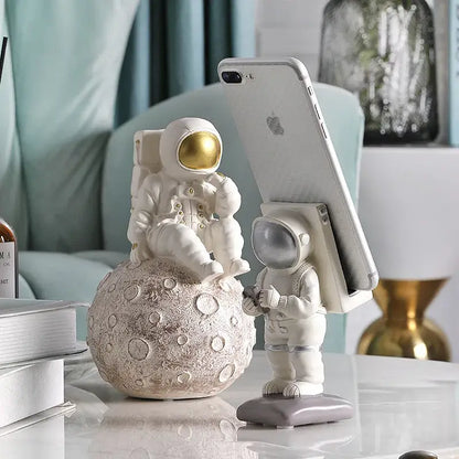 Modern white and gold astronaut phone holder figurine seated on textured moon surface for living room decorbites astronaut phone use
