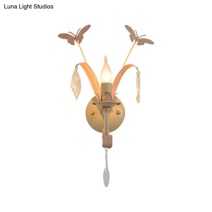 Antique brass wall lamp with white finish, butterfly and leaf accents, crystal droplets, and candle-style bulb for home décor