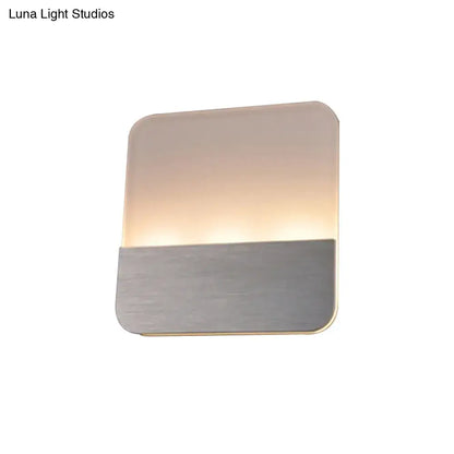 Modern white and silver led sconce light with frosted glass top and brushed metal base emitting warm glow for bedroom