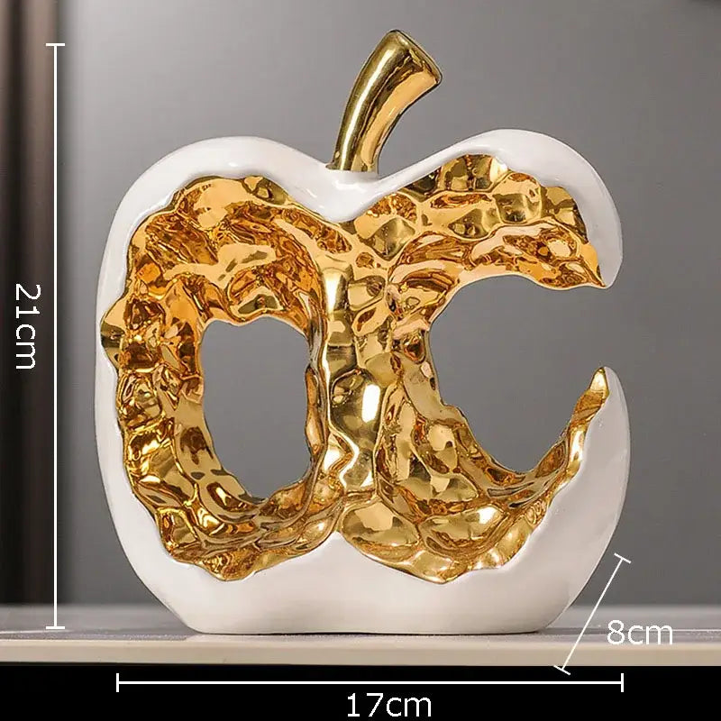 Modern white ceramic apple sculpture with textured metallic gold interior and stem for desk decoration or living room display