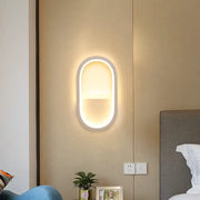 Modern wall lamp with oval white frame and warm white diffused led lighting for bedroom use