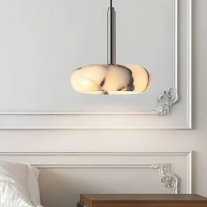 Modern bedside pendant light with a sleek silver stem and an off-white white marble shade with dark veining
