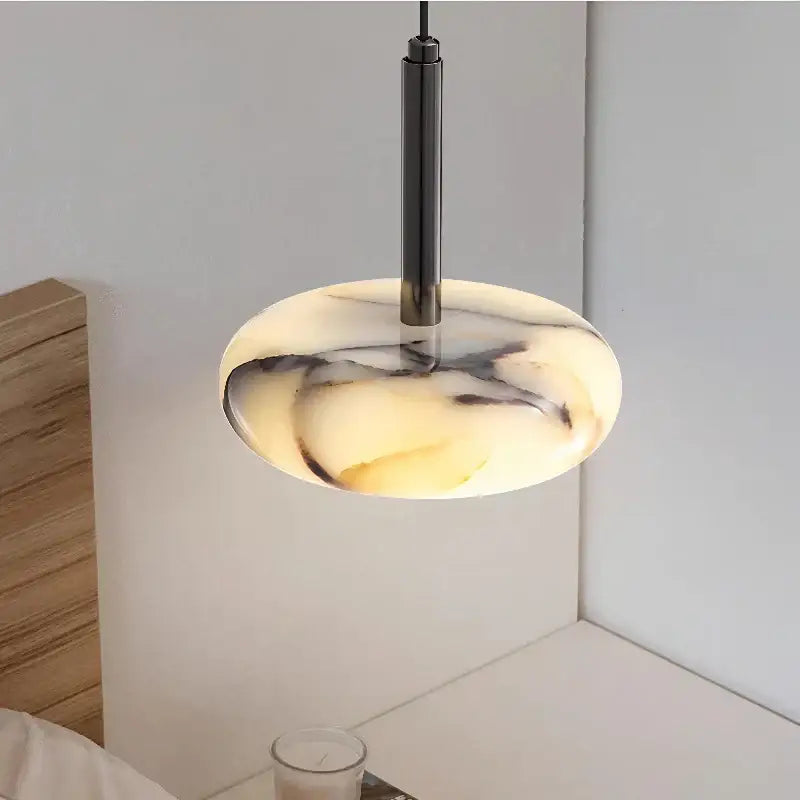 Modern white and black marble bedside pendant light with sleek oval shade suspended by matte black rod