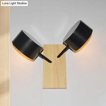 Black matte double drum wall sconce with two cylindrical heads on light wood base fixture height for 220v-240v use