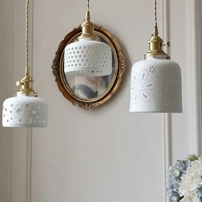 Three white ceramic flower pendant lamps with brass fixtures and decorative perforated patterns for kitchen led lighting