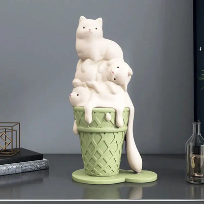 A charming white ceramic cream cat sculpture with three kittens stacked on a mint green ice cream cone for decor