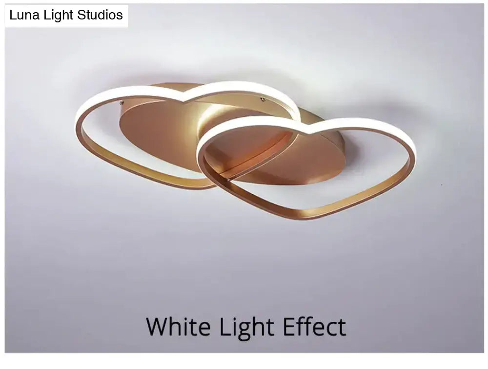 Gold-toned modern white coffee pendant light with two interlocking heart-shaped rings outlined in white led lighting