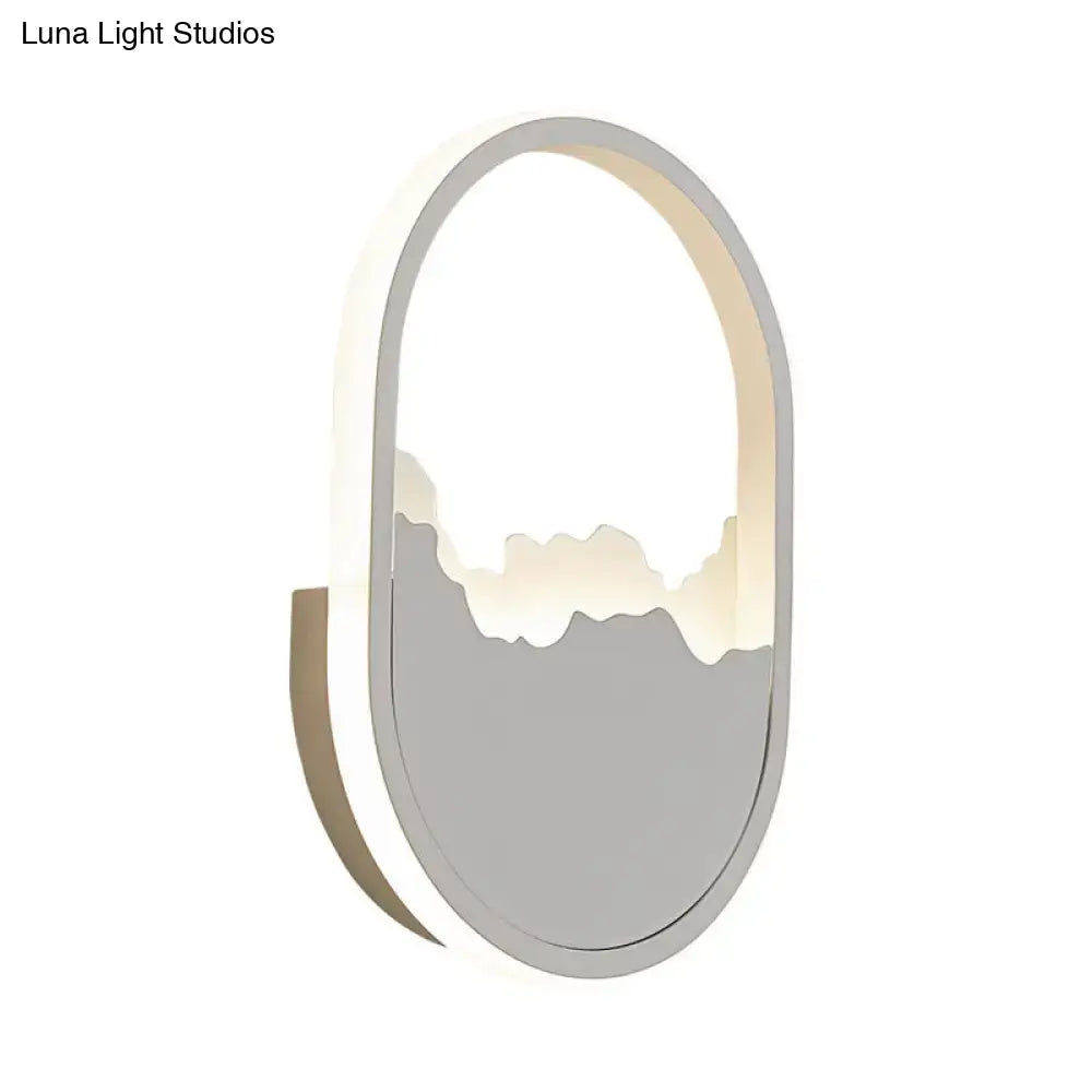 Modern white cracked design oval sconce lamp with gray frame and illuminated mountain silhouette for stairway lighting