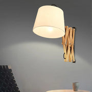 Modern white fabric wall lamp with a warm-toned cylindrical shade and wooden extendable arm for living room lighting