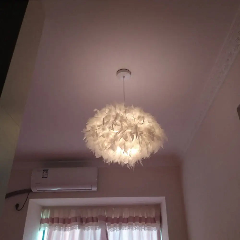 Modern white feather pendant light with chrome finish featuring soft white feathers and warm glow for bedroom use