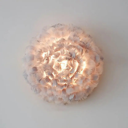 Modern white feather wall sconce featuring a soft circular design with layered feathers radiating a warm glow
