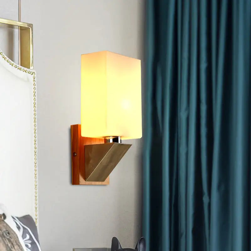 Warm-toned wall lamp with white frosted glass shade and wooden base featuring metal base for modern bedroom use
