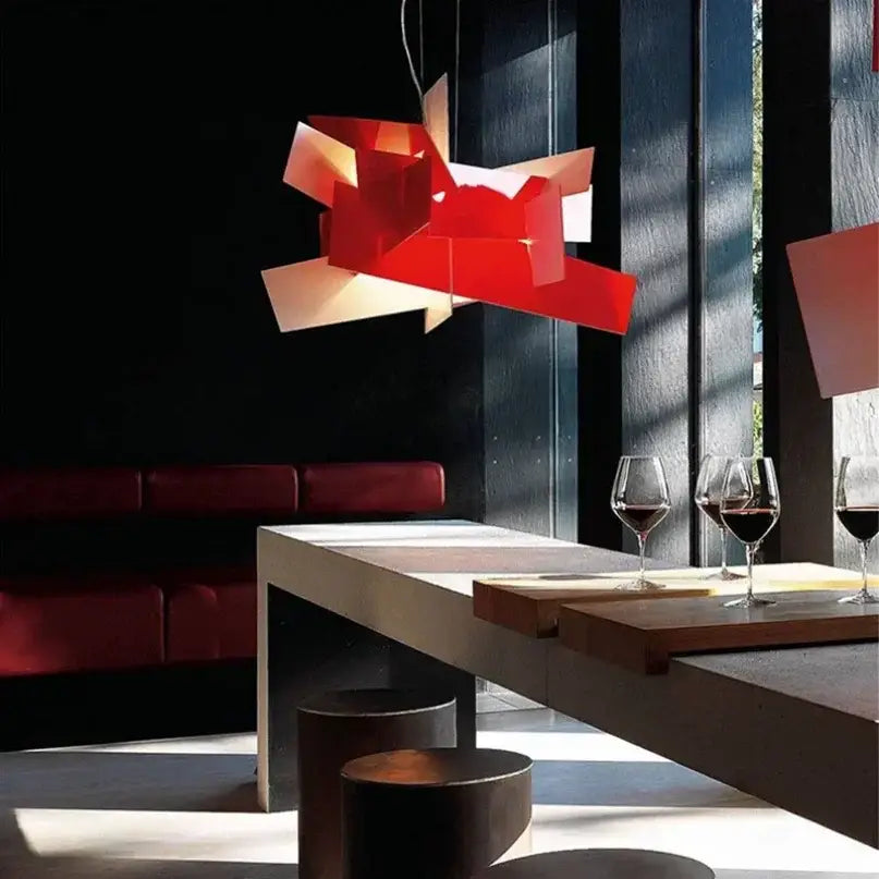 A bold red geometric pendant lamp with angular layered panels suspended above a modern dining table decorbites big bang stacking