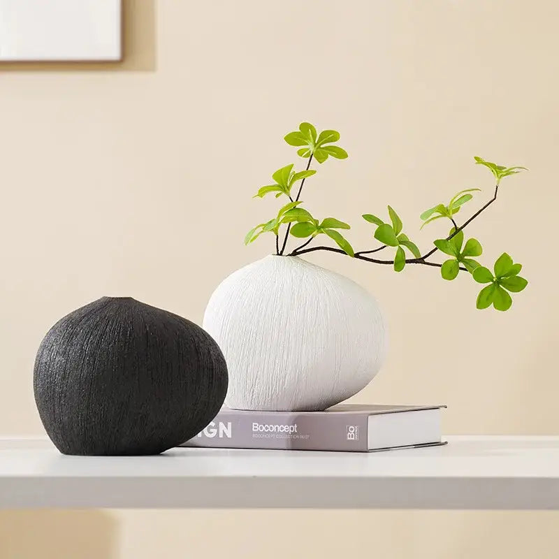 Modern white geometric stripes ceramic vase with sleek rounded form holding delicate green foliage for living room decor