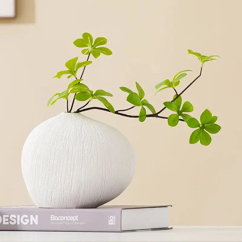 Modern white geometric stripes ceramic vase with textured finish holding a branch with vibrant green leaves decorbites geometric stripes ceramic decor