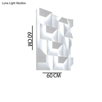Modern white geometric wall lamp with faceted design illuminating living room as decorative art panel