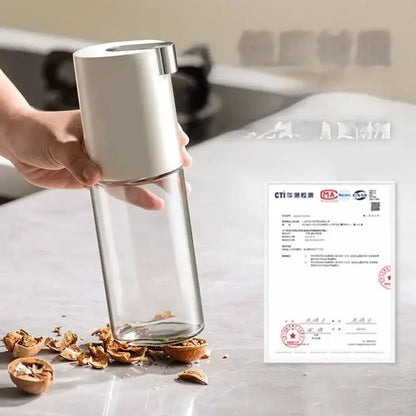 A sleek transparent glass oil pot with a white and silver pump dispenser for modern kitchen seasoning bottle set