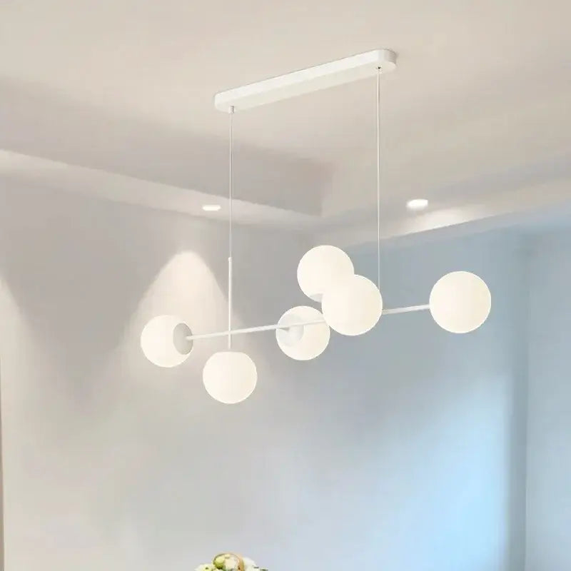 Modern white glass pendant chandelier light set with spherical glass globes and sleek metal frame for dining room