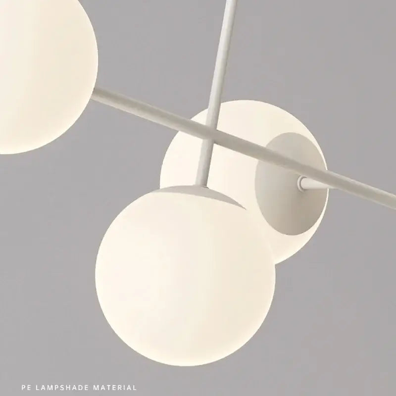 Modern white glass pendant chandelier light set with spherical lampshades suspended from minimalist metal frame