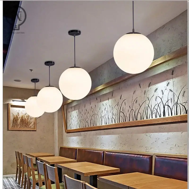 Modern white globe pendant light with white globe shade and black fixtures hanging from ceiling for kitchen dining room