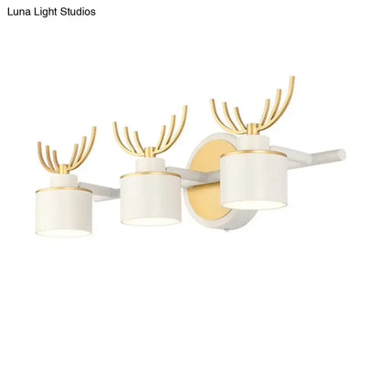 Modern white and gold antler wall light fixture with three cylindrical shades for bathroom vanity lighting