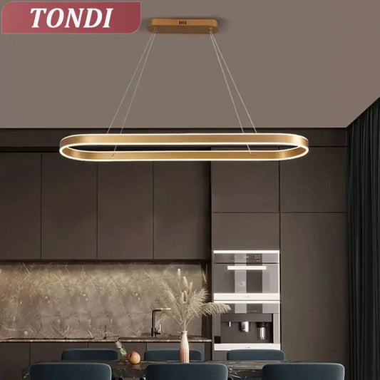 Gold-toned oval led pendant light with a white finish and circular form for modern dining room lighting