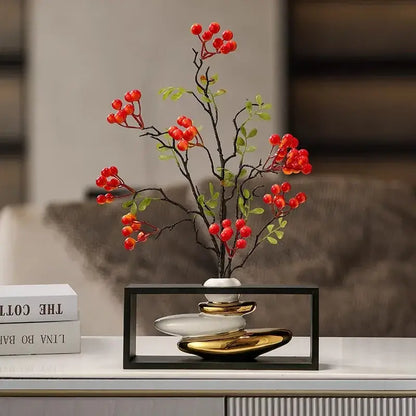 Modern white and gold ceramic vase with sleek layered design holding artificial red berries in geometric golden rockery decorbites