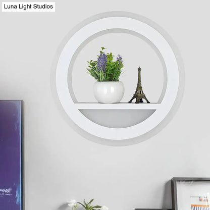 Modern white halo ring wall light fixture with glossy circular shelf holding white ceramic pot and miniature eiffel tower