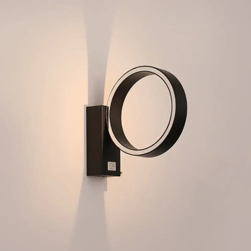 Modern black circular wall sconce with sleek minimalist design and direct wired power source for living room use