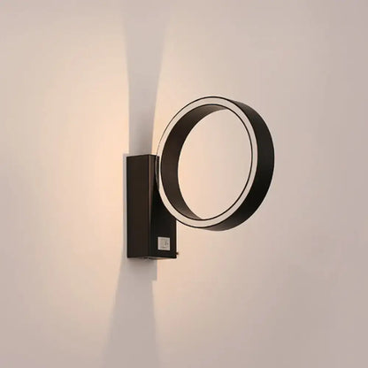 Modern black circular wall sconce with sleek minimalist design and direct wired power source for living room use