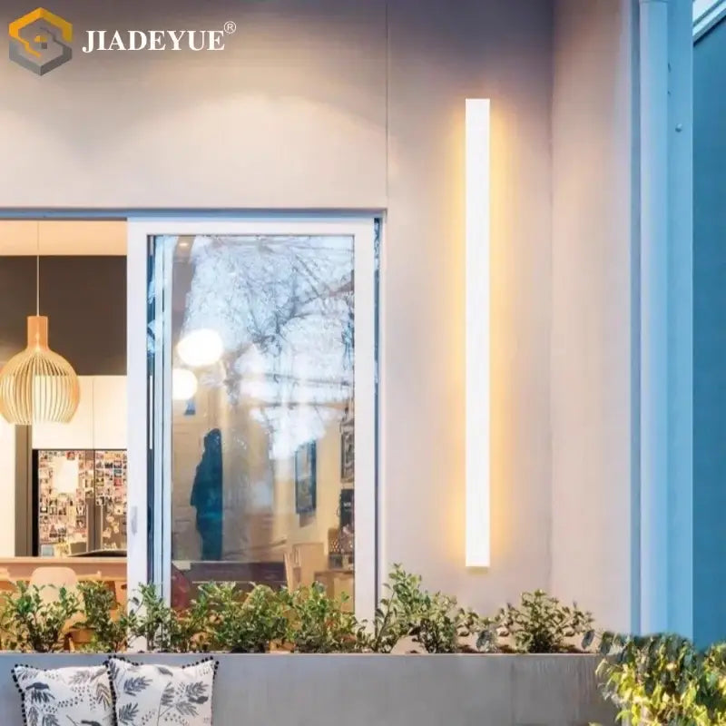 A sleek modern white led waterproof garden wall lamp from decorbites emitting a warm glow as an outdoor sconce