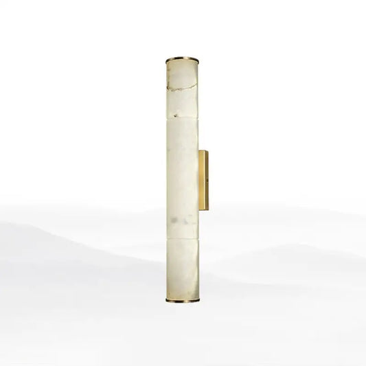 A tall cylindrical wall lamp with a translucent white marble body and polished brass accents for living room use