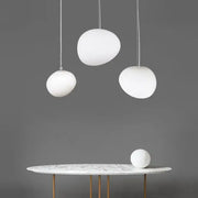 Modern white matte glass pendant lights with egg-shaped design hanging above a marble table for living room use
