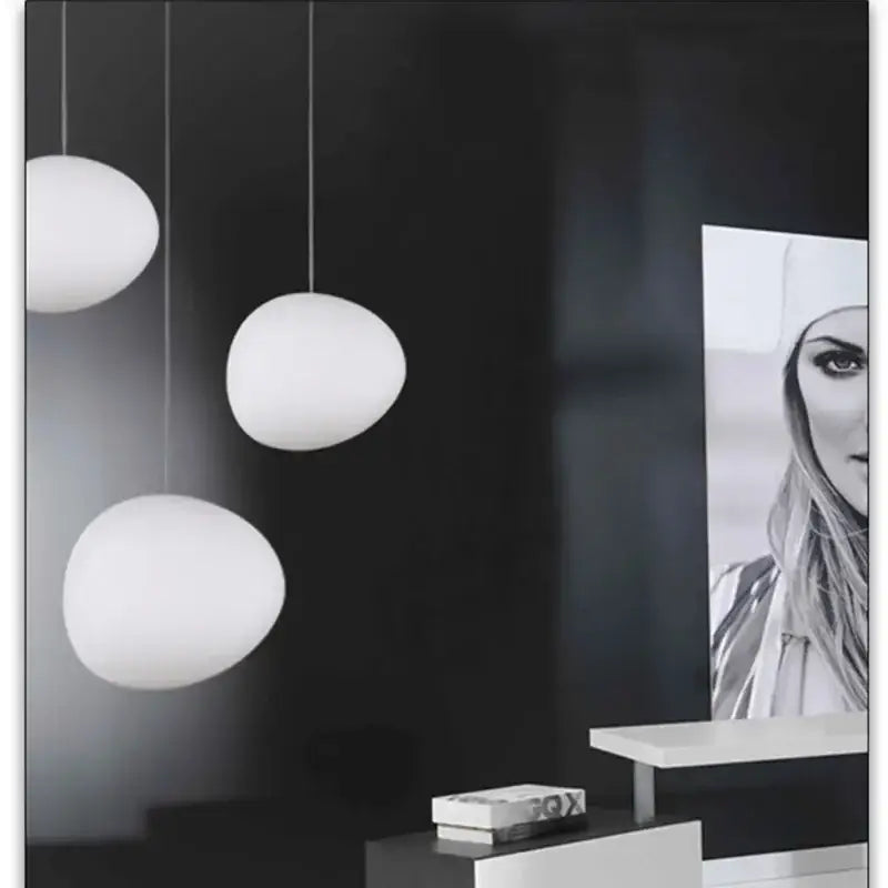 Three white matte glass pendant lights with egg-shaped design hanging from the ceiling for living room use