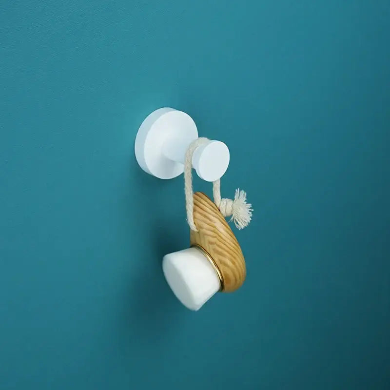 Wooden-handled facial cleansing brush with white silicone head and gold ring hanging on decorbites bathroom accessory set hook